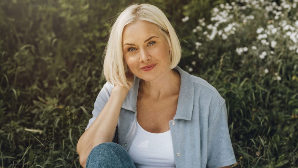 Mature blond woman sitting in a grass field