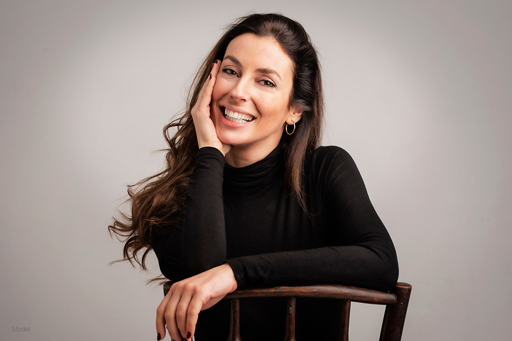 Woman in a black long sleeve shirt leaning on a chair