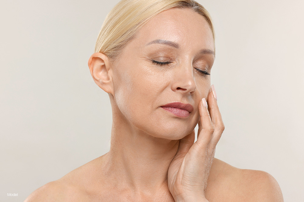 A mature woman touching her face